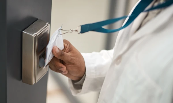 Une personne utilise une carte d'acc&egrave;s blanche pour d&eacute;verrouiller une serrure &eacute;lectronique dor&eacute;e sur une porte grise moderne