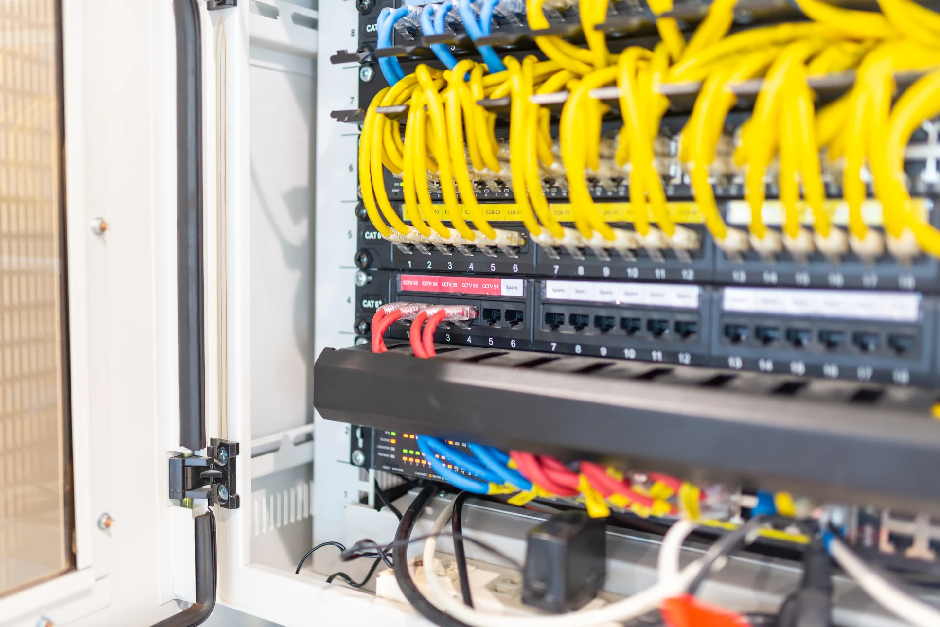 Intérieur de datacenter avec technicienne en chemise bleue utilisant une tablette tactile pour surveiller les équipements réseau