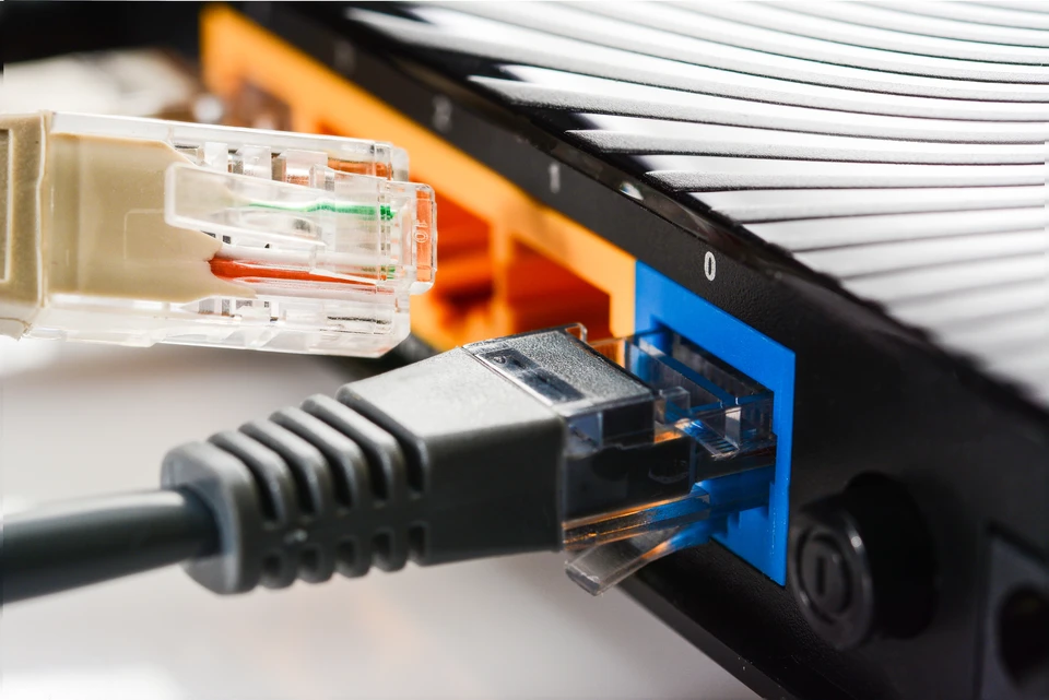Technicien informatique travaillant dans un datacenter, manipulant des équipements réseau dans une baie serveur ouverte